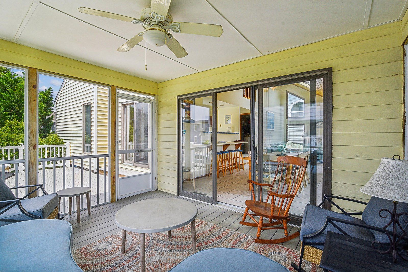 A covered patio with a table, chairs, and a ceiling fan.