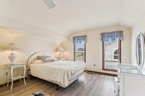 A bedroom with a bed, two bedside tables, a dresser, and a window with blinds.