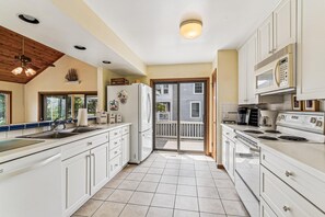 Une cuisine avec des meubles blancs, un réfrigérateur, une cuisinière et un four à micro-ondes.
