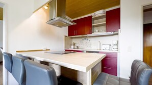 Una cocina moderna con una isla central, armarios rojos y una campana extractora de acero inoxidable.