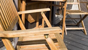 Una terraza de madera con una mesa y dos sillas, una decoración con forma de estrella y una ventana con vistas a árboles.