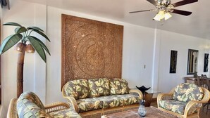 A living room with wicker furniture, a ceiling fan, and a decorative wall panel. - Puerto Nuevo Villa Olas 2BR 2BA with pool (Centro Turístico El Pescador)