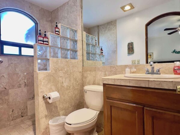 Une salle de bain comprenant des toilettes, un lavabo et un espace douche.