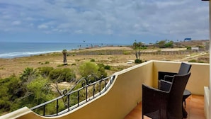 A balcony with a view of the beach and ocean.