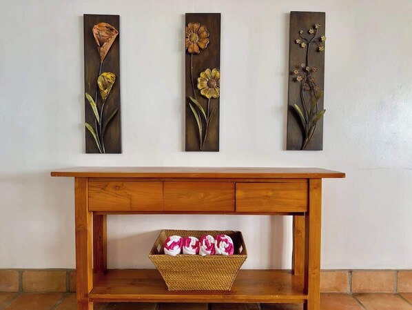 A wooden console table with a woven basket containing pink and white flowers.