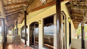 Un espacio al aire libre techado, con techo de madera, ventanas amplias y un banco.