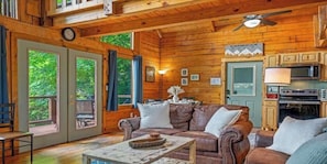 A wooden cabin interior with a dining area, a sofa, and a kitchen.
