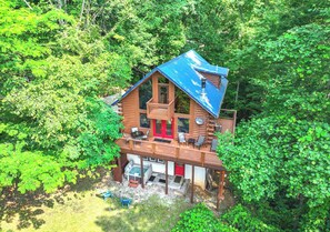 A cabin with a balcony, a hot tub, and a covered deck area.