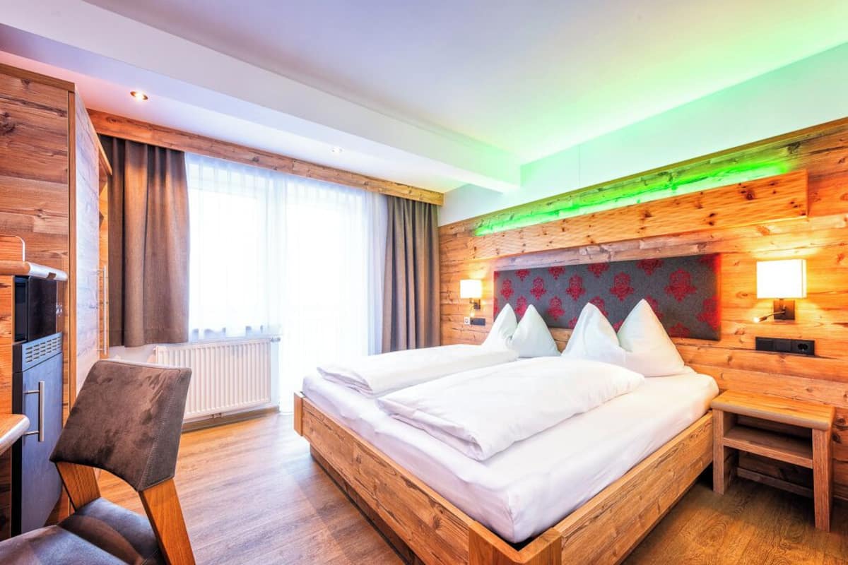 Ein modernes Hotelzimmer mit einem hölzernen Bett, einem Schreibtisch und einem Stuhl.