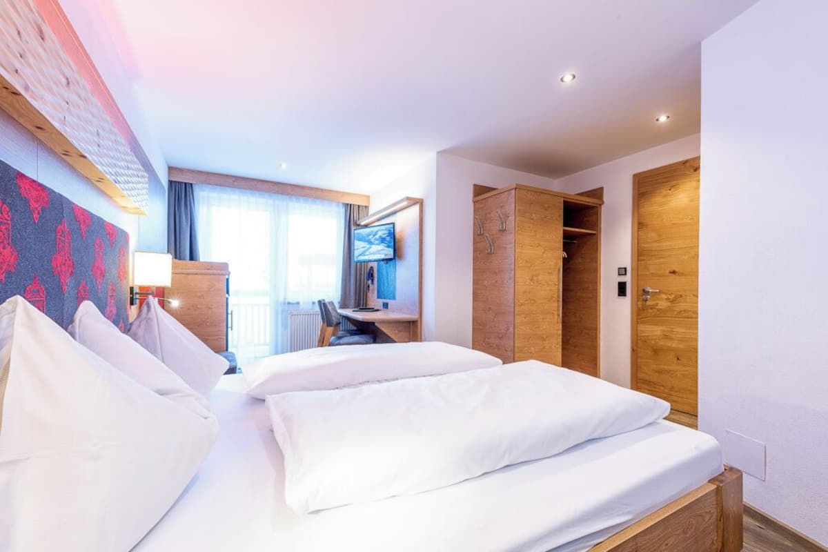 Ein Hotelzimmer mit zwei Betten, einem Schreibtisch, einem Fernseher und einem Kleiderschrank.