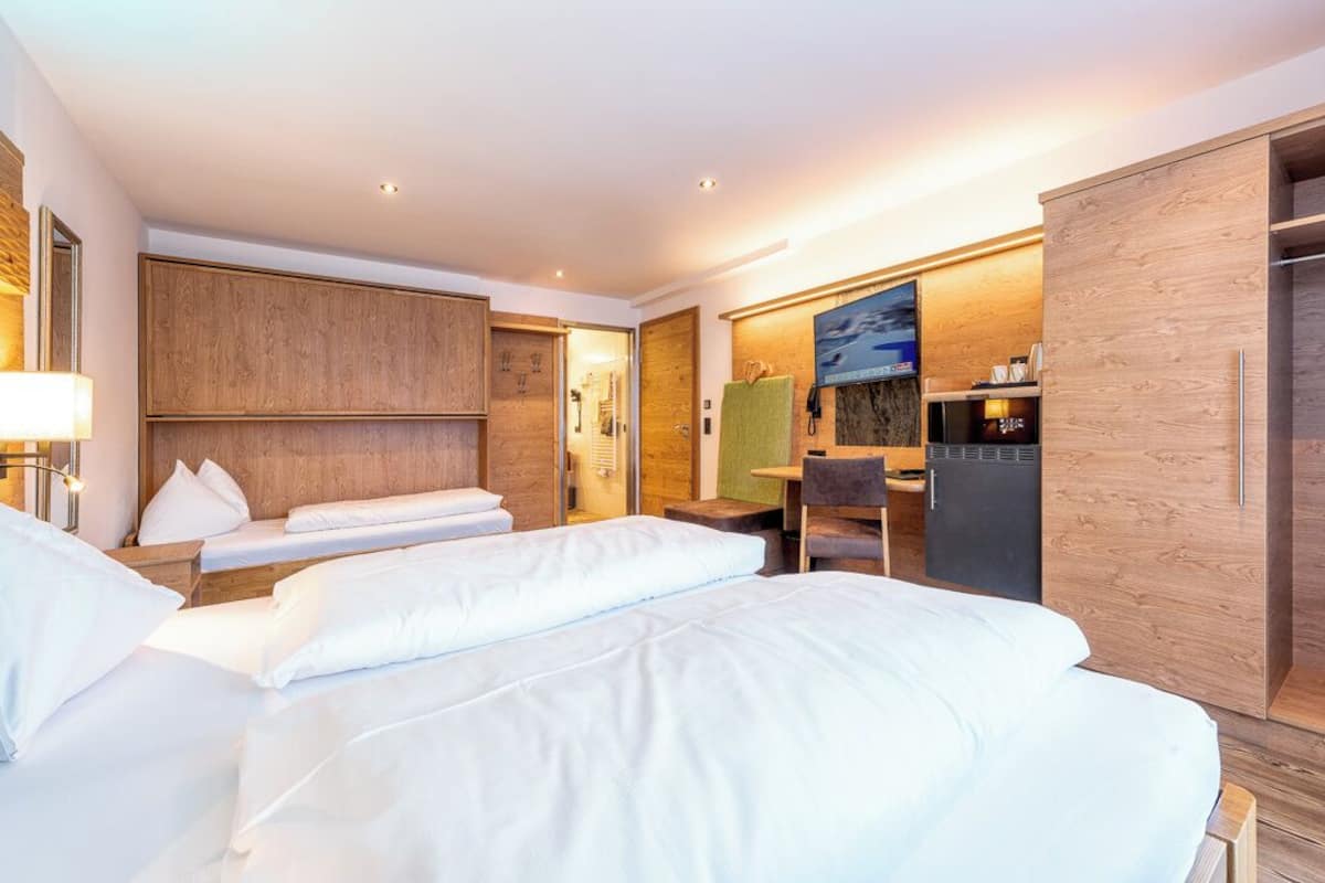 Ein Hotelzimmer mit zwei Betten, einem Schreibtisch, einem Spiegel und einem Kleiderschrank.