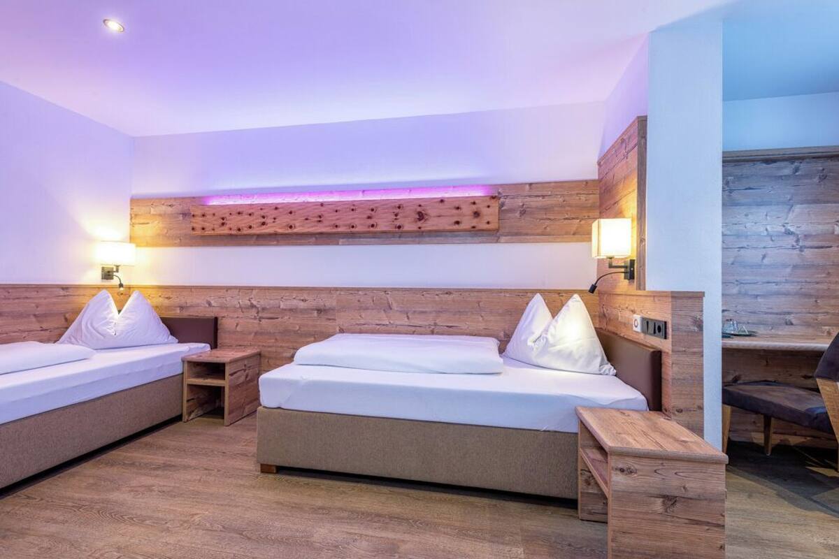 Ein modernes Hotelzimmer mit zwei Betten, einem Holzkopfstück und einem integrierten Schreibtisch.