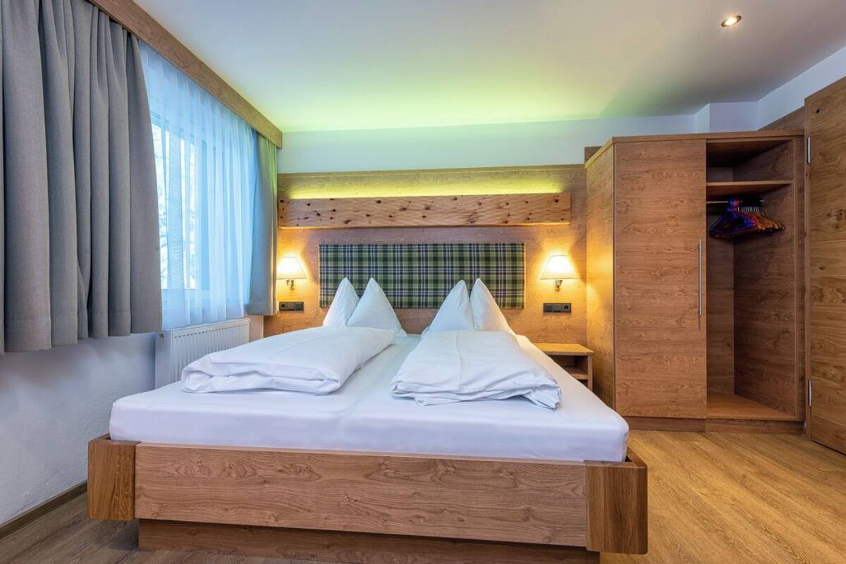 Ein modernes Schlafzimmer mit einem hölzernen Bett, einem Karomuster-Kopfteil und eingebauten Schränken.