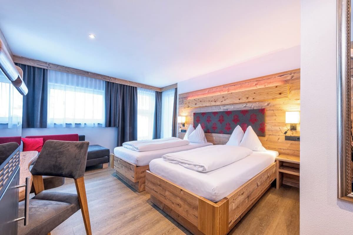 Ein Hotelzimmer mit zwei Holzbett, einem Schlafsofa, einem Schreibtisch und einem Stuhl.