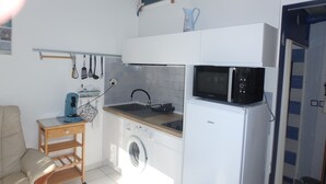 A compact kitchen with a washing machine, a microwave, and a sink. - 2mns walk to beach, shops and entertainment, 2**apart 2pers, air-conditioned, large terrace. (Argelès-sur-Mer)