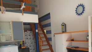 A compact kitchen with a dining area, a small refrigerator, a microwave, and a wooden staircase. - 2mns walk to beach, shops and entertainment, 2**apart 2pers, air-conditioned, large terrace. (Argelès-sur-Mer)