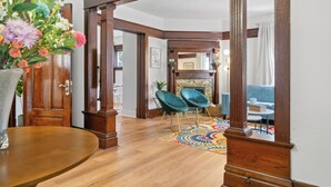 A spacious living room with a wooden floor, a fireplace, and a colorful rug.