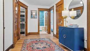 A hallway with wooden doors, a blue cabinet, a rug, and a mirror.