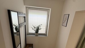 A corner room with a wooden bench, a window with blinds, a potted plant, and a framed picture on the wall. - Super nice and extremely large apartment approx. 145 m² in a country house in Priorei (Hagen)