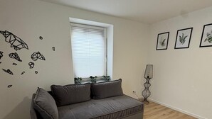 A modern living room with a grey sofa, a window with blinds, and three framed botanical prints on the wall. - Super nice and extremely large apartment approx. 145 m² in a country house in Priorei (Hagen)