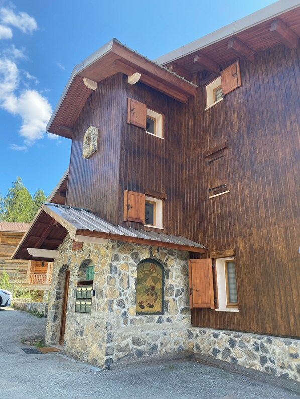 A multi-story wooden building with stone accents and wooden shutters.