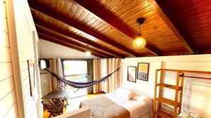 A cozy attic bedroom with a hammock, a bed, a ladder, and a desk. - Chalés Santa Marta (Laguna)