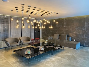 A modern living room with a black coffee table, two armchairs, a sofa, and a decorative light fixture. - Bela Hospedagem - 607 One Way Tambau (Joao Pessoa)