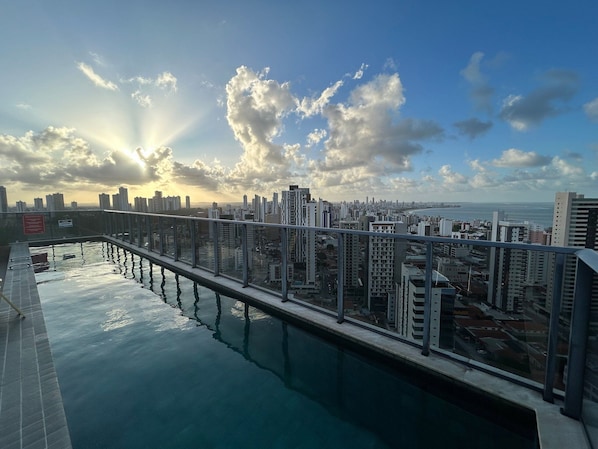 A rooftop pool with a cityscape view, including high-rise buildings and a body of water. - Bela Hospedagem - 607 One Way Tambau (Joao Pessoa)