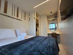 Una habitación de hotel con una cama, un espejo redondo y un escritorio.