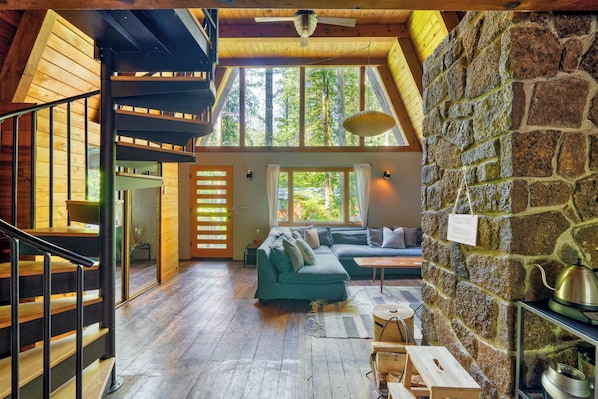 Ein geräumiges Loft mit einer Holztreppe, einer grünen Sofagarnitur und einer Steinwand.