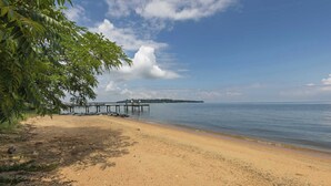 A beach with a wooden pier extending into calm waters, surrounded by greenery and a clear sky. - Pool Loft Suite | Bay Access & Beach Passes (Annapolis)