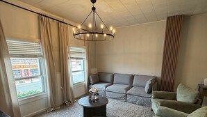 A living room with a sectional sofa, a round coffee table, and a chandelier. - Historic Main Street Apartment A in Panguitch Utah (Panguitch)