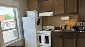 A kitchen with a refrigerator, stove, and microwave. There is a window with a view of a building outside. - Historic Main Street Apartment A in Panguitch Utah (Panguitch)
