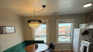 A compact kitchen with a dining table, a green sofa, and a chandelier. - Historic Main Street Apartment A in Panguitch Utah (Panguitch)