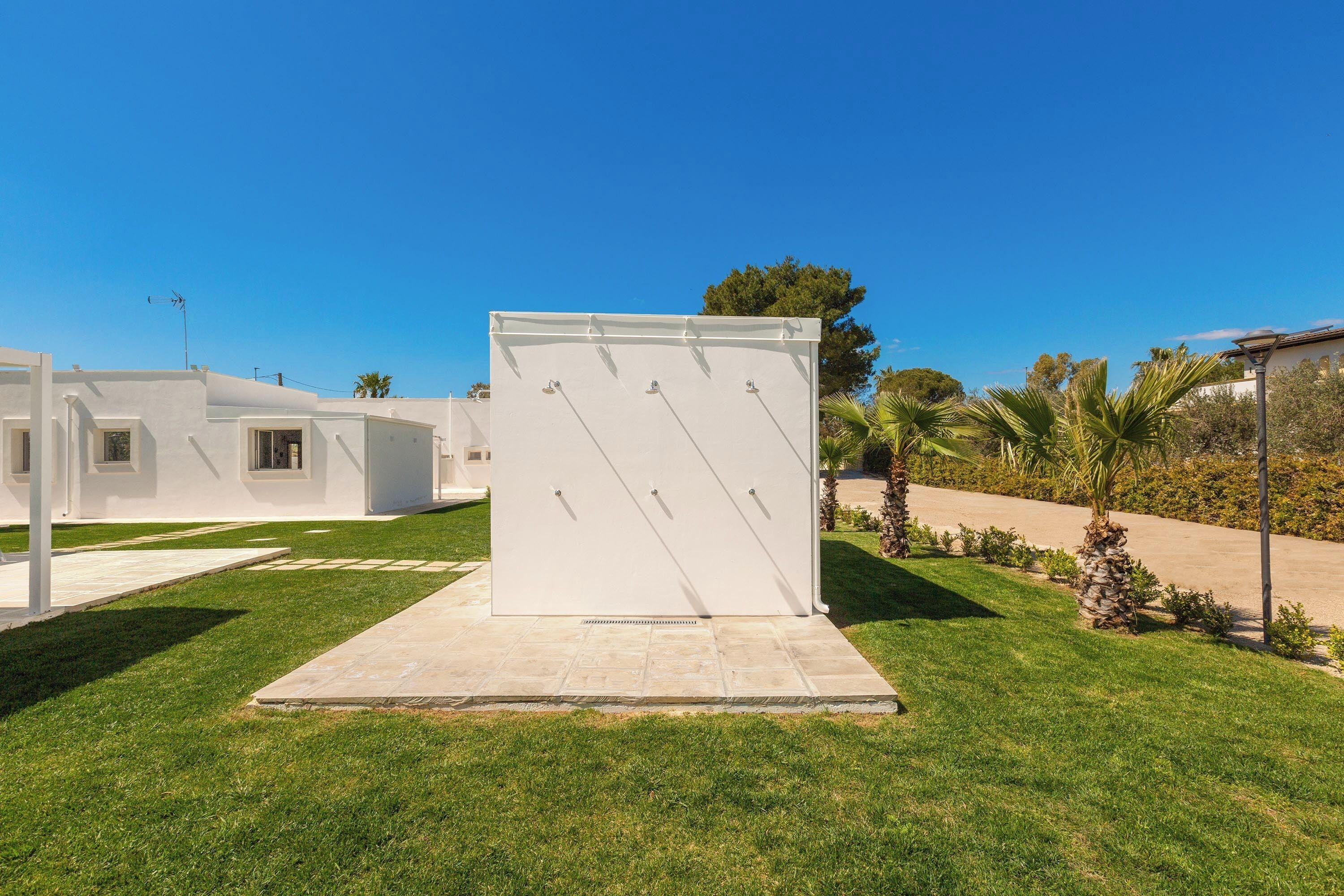 A modern building with a flat roof, a paved entrance, and a well-maintained lawn.