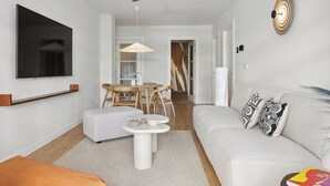A modern living room with a flat-screen TV, a ceiling fan, a dining area with a table and chairs, and a sofa with decorative pillows. - Ulia Terrace by FeelFree Rentals (San Sebastian)
