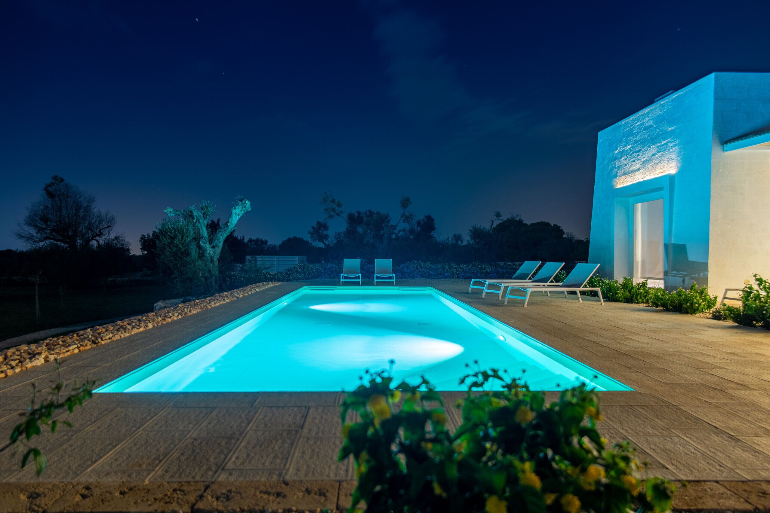 Ein rechteckiger Pool mit glatter Oberfläche und einer klaren blauen Kante, umgeben von einer Holzterrasse.