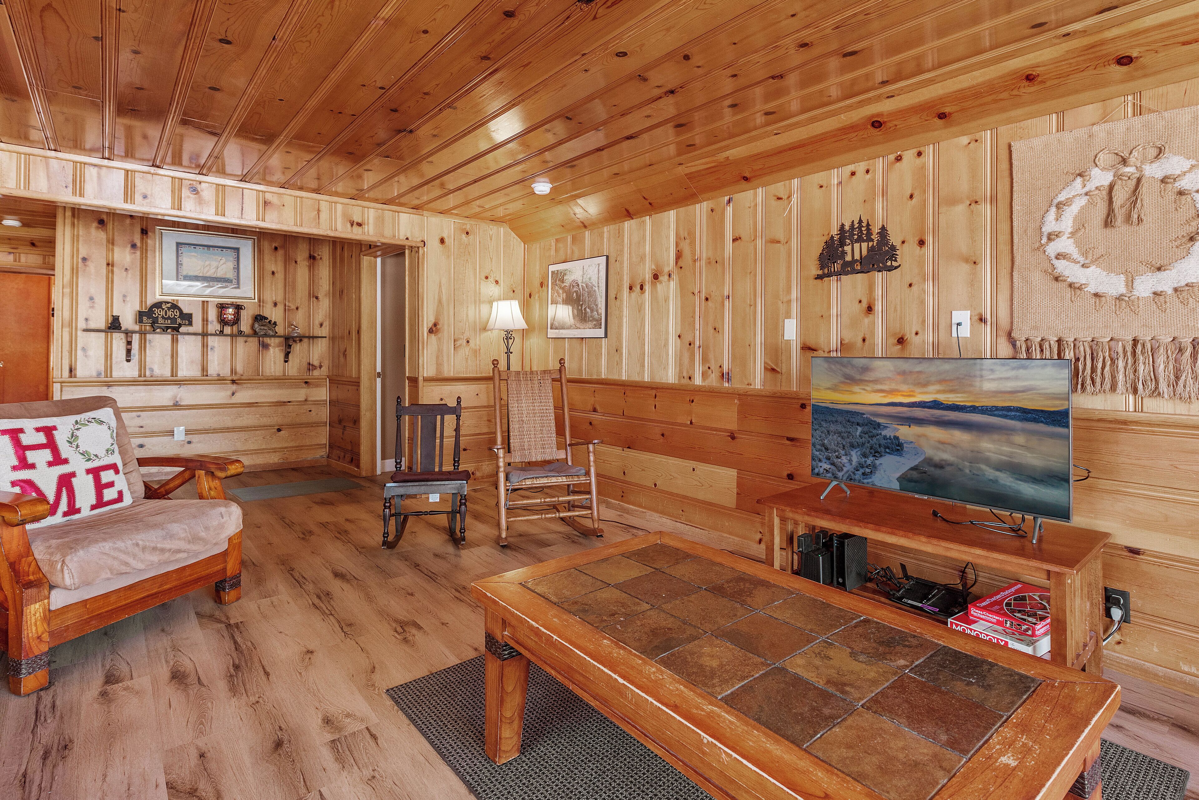 Un intérieur en bois avec un canapé, un fauteuil et un téléviseur posé sur un meuble en bois.