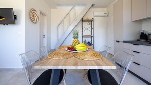 Eine moderne Küche mit Esstisch für vier Personen, ausgestattet mit gewobenen Platzsets, einer Ananas, Bananen und Trauben.