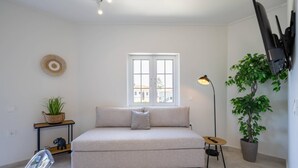 Ein schlicht eingerichtetes Schlafzimmer mit Bett, Fenster, Lampe und Topfpflanze.