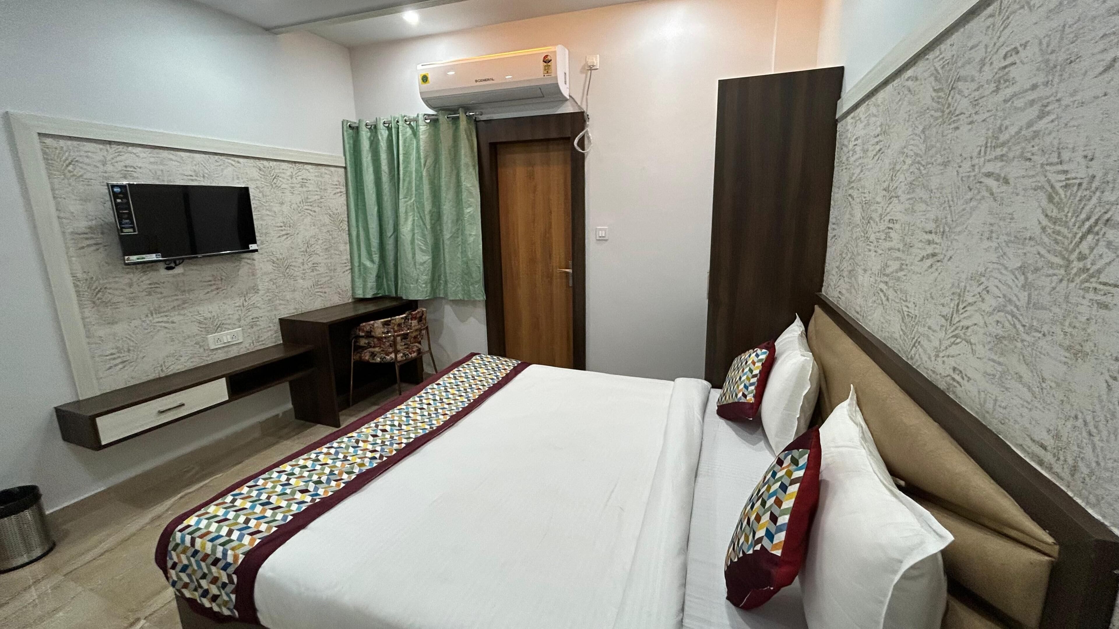 A bedroom with a bed, a TV, a desk, and a wardrobe.