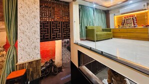 A room with a green sofa, a wooden cabinet, and a decorative partition with a geometric pattern. - SANIDHYAM by HOTEL SAHU (Varanasi)
