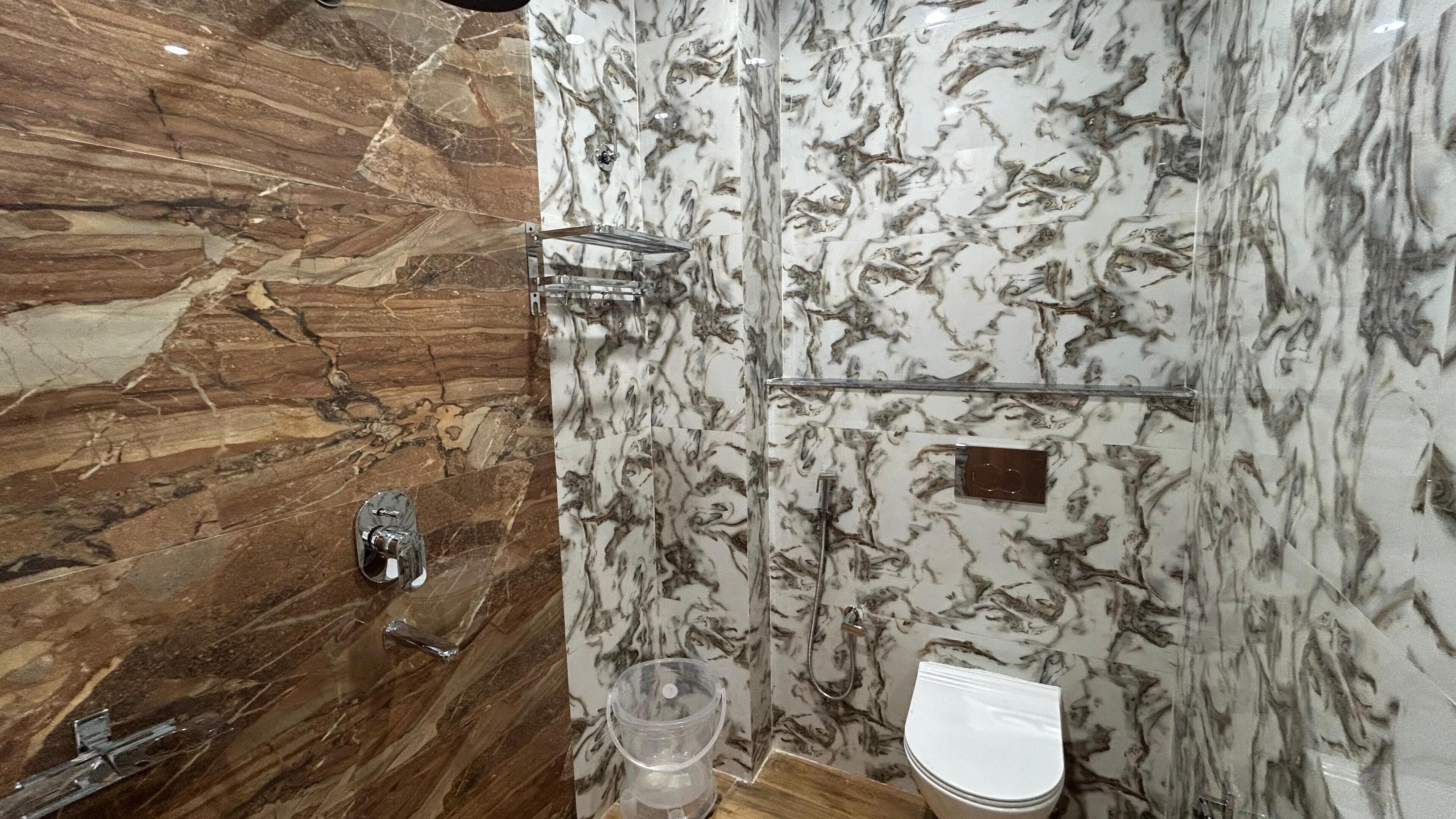 Ein Badezimmer mit Marmorwänden, einer Duschkabine und einer Toilette.