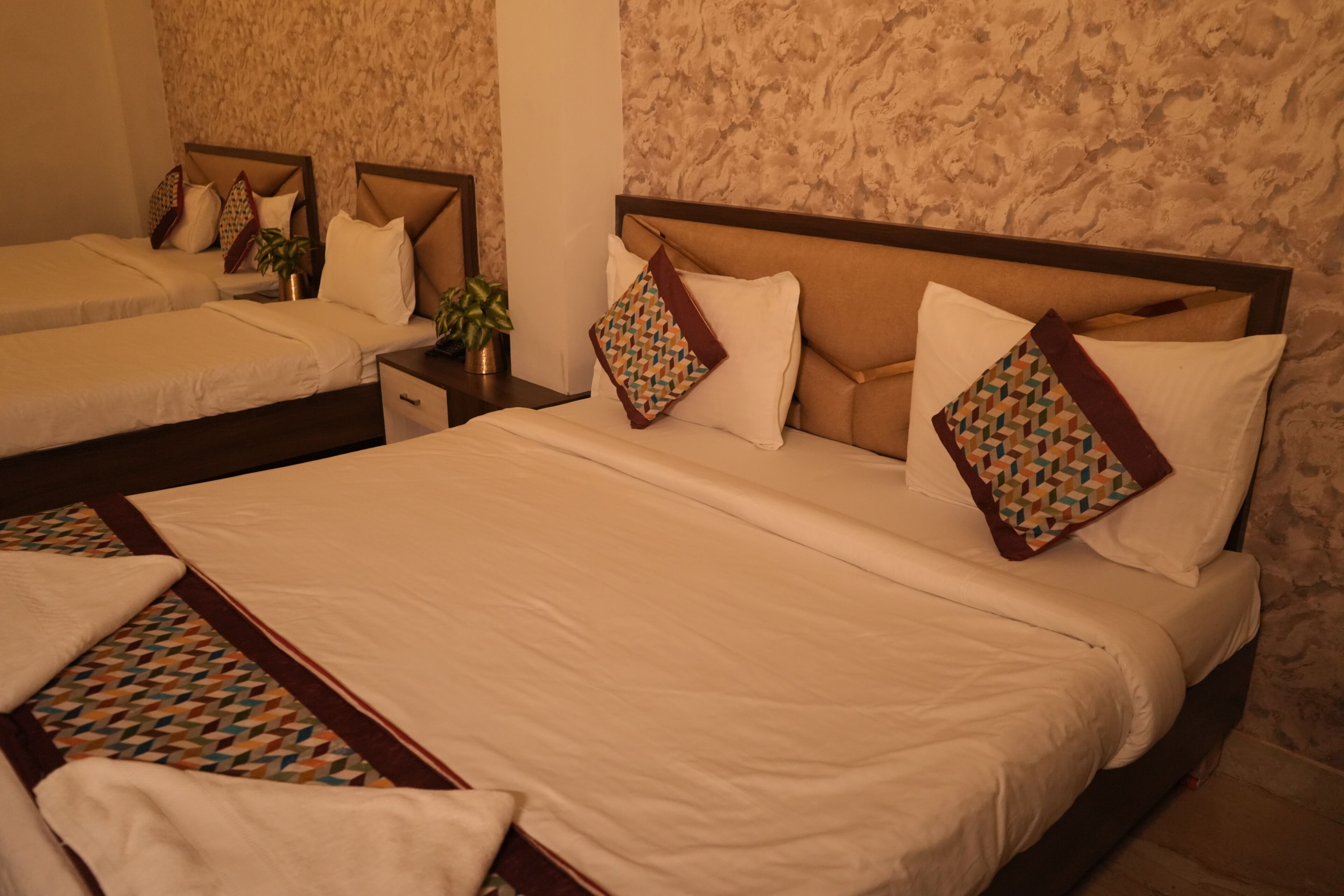 A hotel room with two beds, a nightstand, and a wall with a textured pattern.