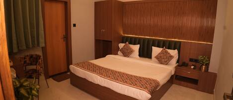 A modern bedroom with a large bed, a wooden headboard, a bedside table, and a chair.