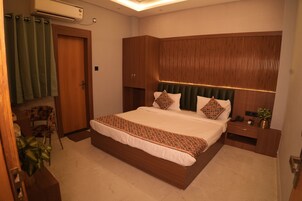 A modern bedroom with a large bed, a wooden headboard, a bedside table, and a chair.