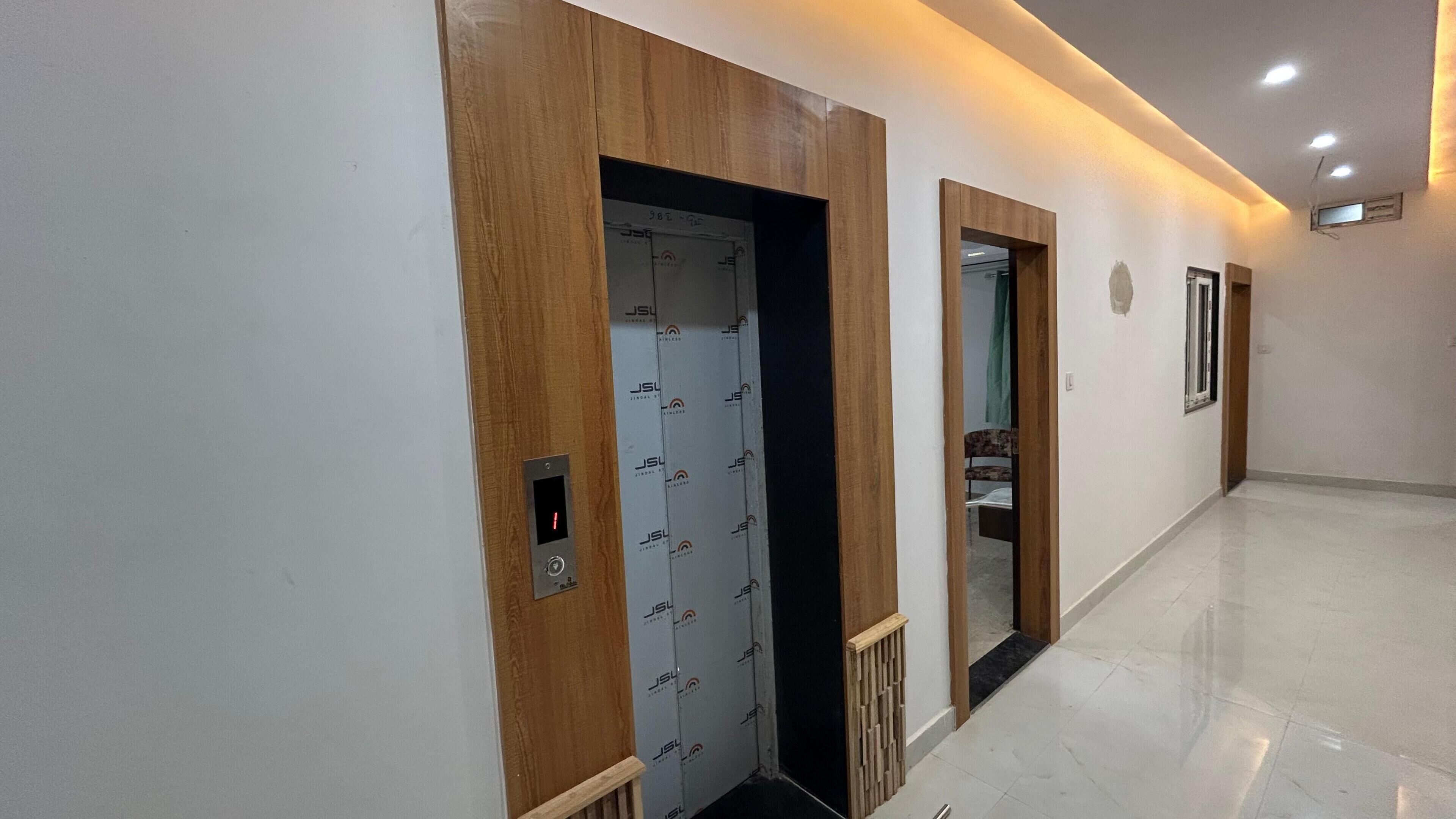 A hallway with a wooden door and a mirrored wall.