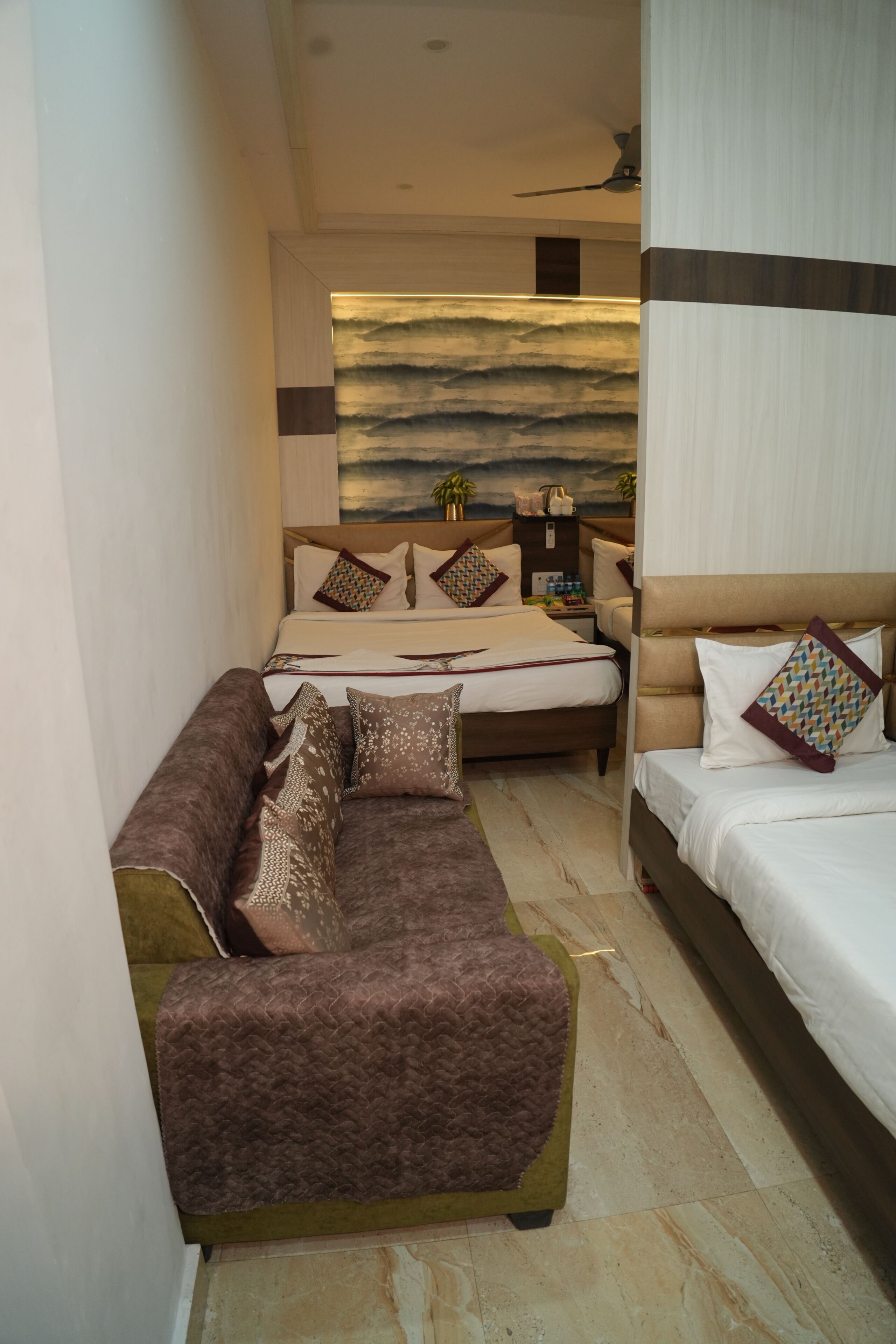 A bedroom with a bed, a sofa, a bedside table, and a wall with a painting.