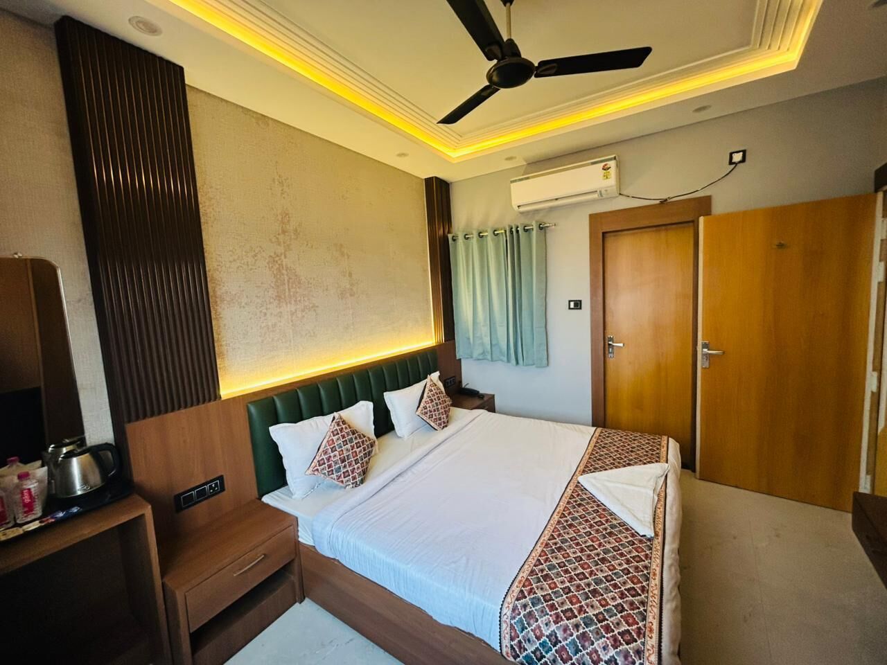 A hotel room with a bed, bedside table, wardrobe, and an air conditioning unit.