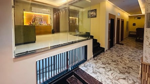 A hotel lobby with a glass partition, a reception desk, and a marble floor. - SANIDHYAM by HOTEL SAHU (Varanasi)
